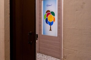 Een deur met een geëtste glazen paneel waarop een kleurrijke boom en de tekst 'Room 1' staan.