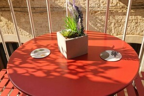 Mesa redonda con una planta en maceta y dos posavasos.
