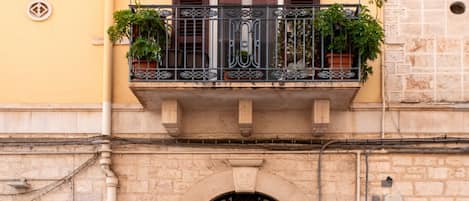 A building with a balcony with metal railings and potted plants.