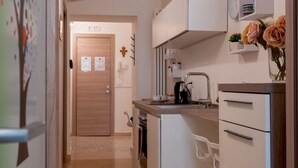 Una cocina compacta con refrigerador, cafetera y lavamanos.