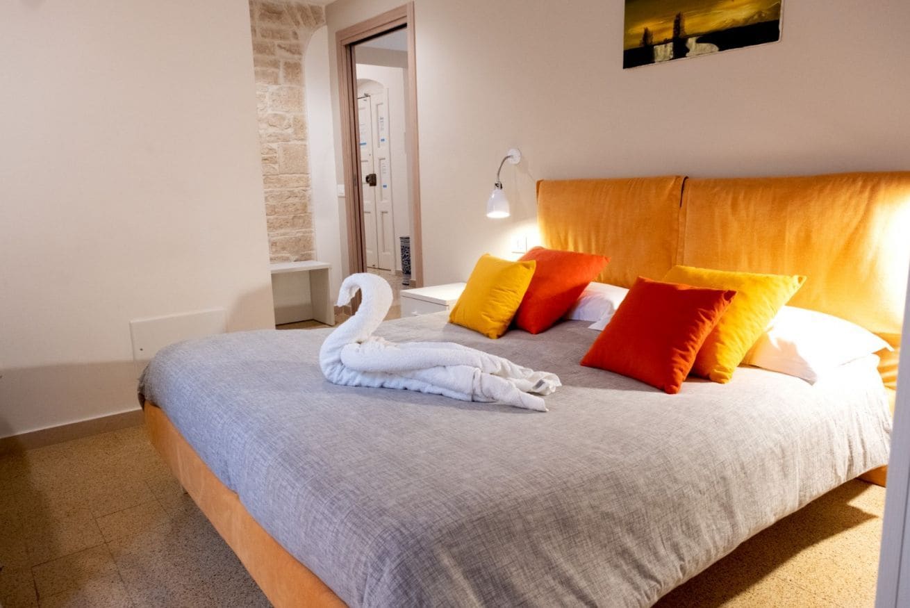 A bedroom with a bed, a swan towel, and a painting on the wall.