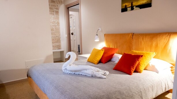 Un dormitorio con cama, toalla con forma de cisne y un cuadro en la pared.