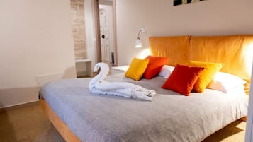 A bedroom with a bed, a swan towel, and a painting on the wall.