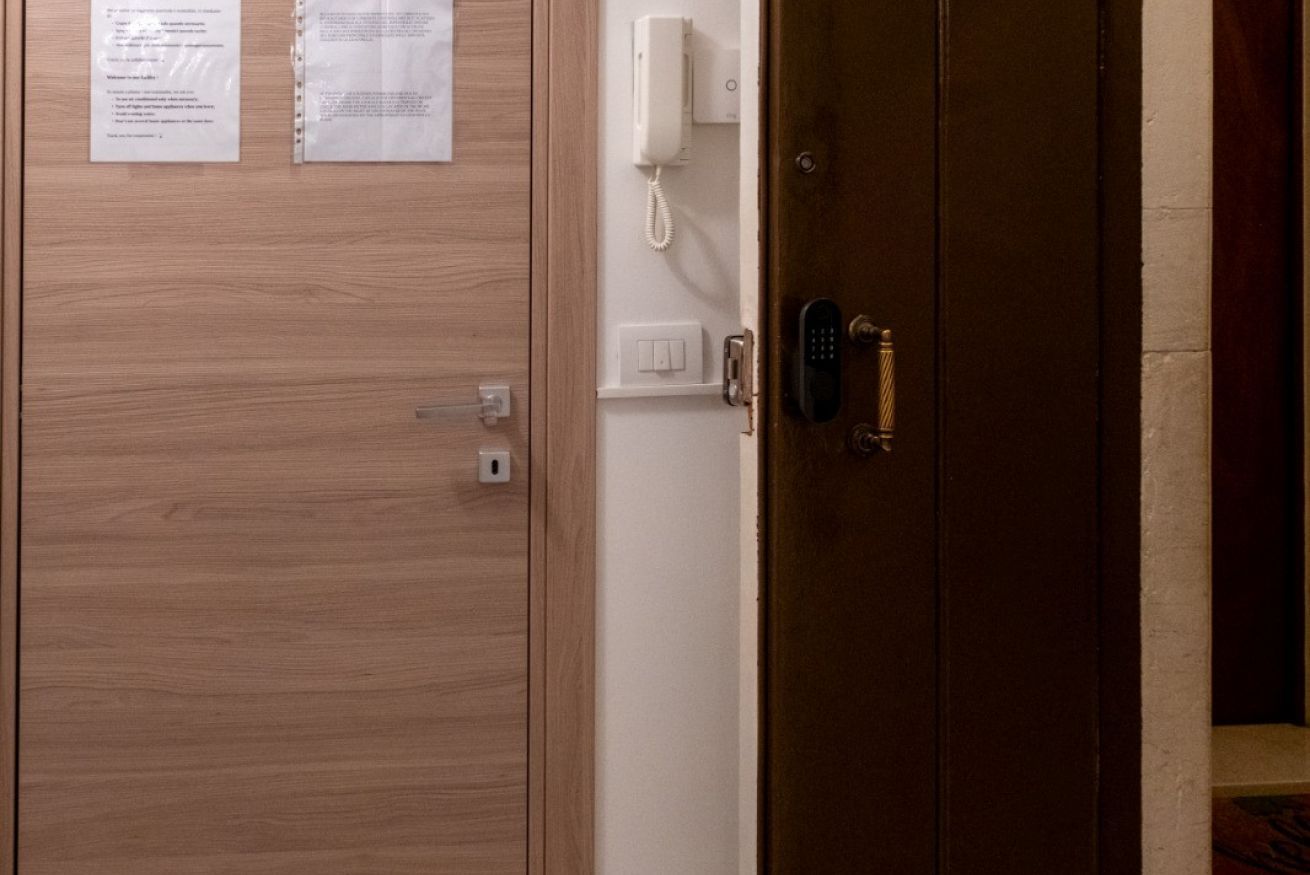 Une porte en bois avec une serrure, un téléphone blanc fixé au mur et un interrupteur.