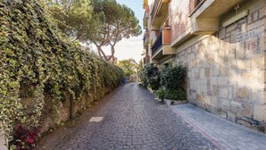 A narrow cobblestone street flanked by buildings with stone walls and some greenery. - Charming Apt with Garden and Park (Rome)