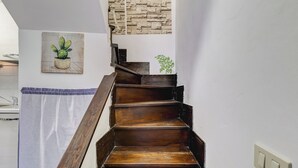 A wooden staircase with a white wall and a small potted plant on the landing. - Charming Apt with Garden and Park (Rome)