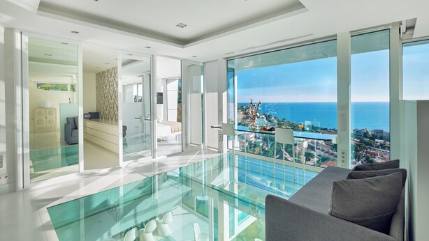 A modern interior with a glass floor leading to a balcony with a city and sea view. - Villa in Sitges |Pool|Jacuzzi|BBQ|Views|AC|12P (Sitges)