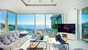 A modern living room with a large sofa, a coffee table, and a TV displaying 'NETFLIX'. - Villa in Sitges |Pool|Jacuzzi|BBQ|Views|AC|12P (Sitges)