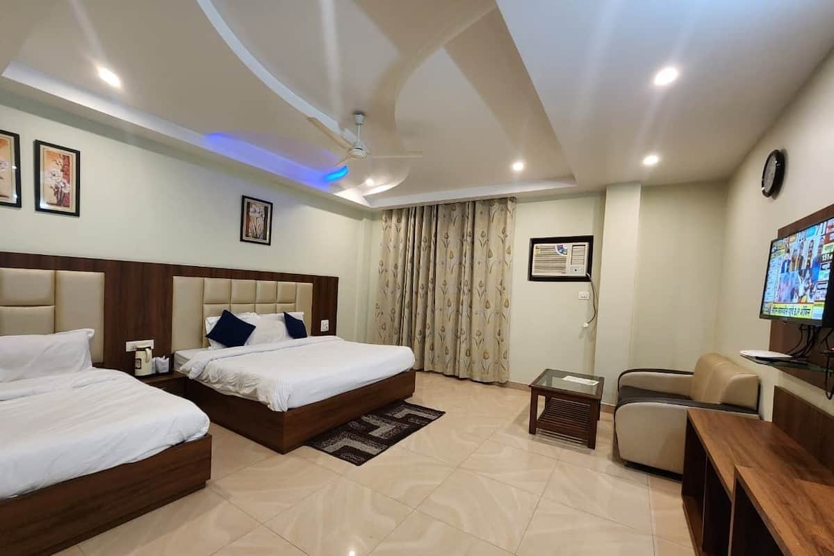 A hotel room with two beds, a TV, a desk, and a chair.