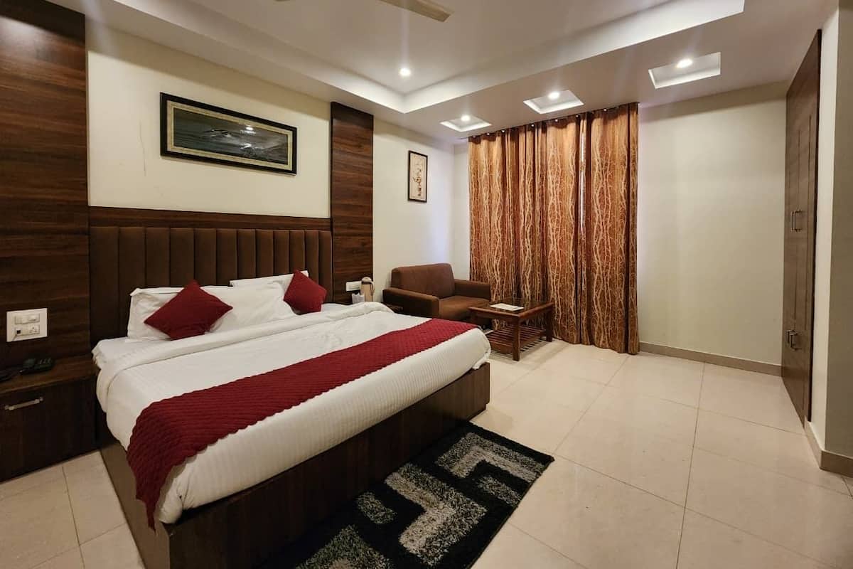 A modern bedroom with a large bed, a nightstand, a chair, a desk, and a wardrobe.