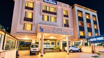 A hotel with a modern facade, multiple balconies, and a well-lit entrance.
