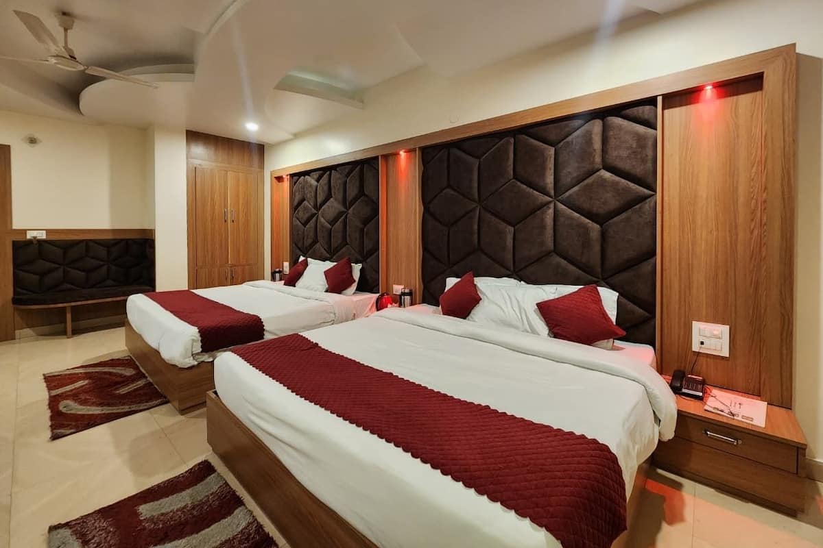 A hotel room with two beds, a wooden headboard, a red accent wall, and a ceiling fan.