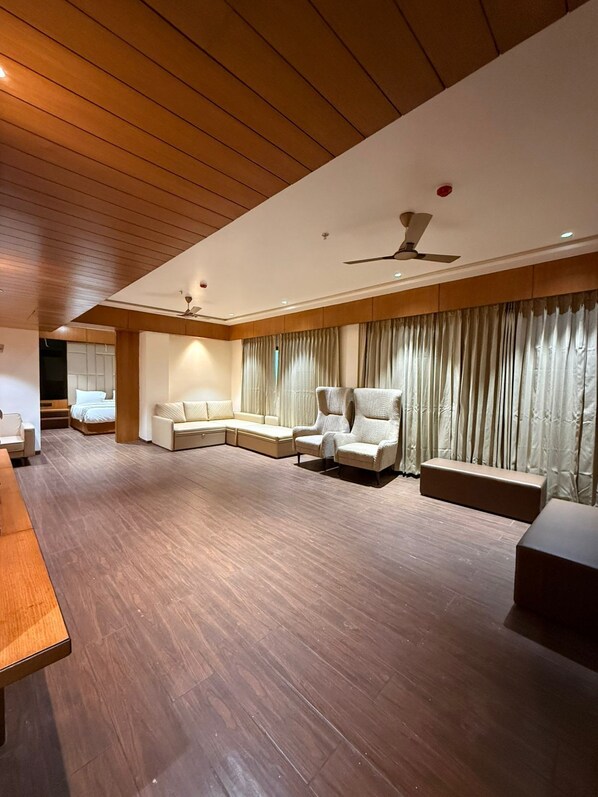 A modern living room with a wooden ceiling, a ceiling fan, a sofa, a chair, and a coffee table. - Hariganga S The Lake Attitude (Amravati)
