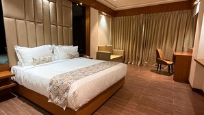 A modern hotel room with a large bed, a desk, a chair, and a ceiling fan. - Hariganga S The Lake Attitude (Amravati)