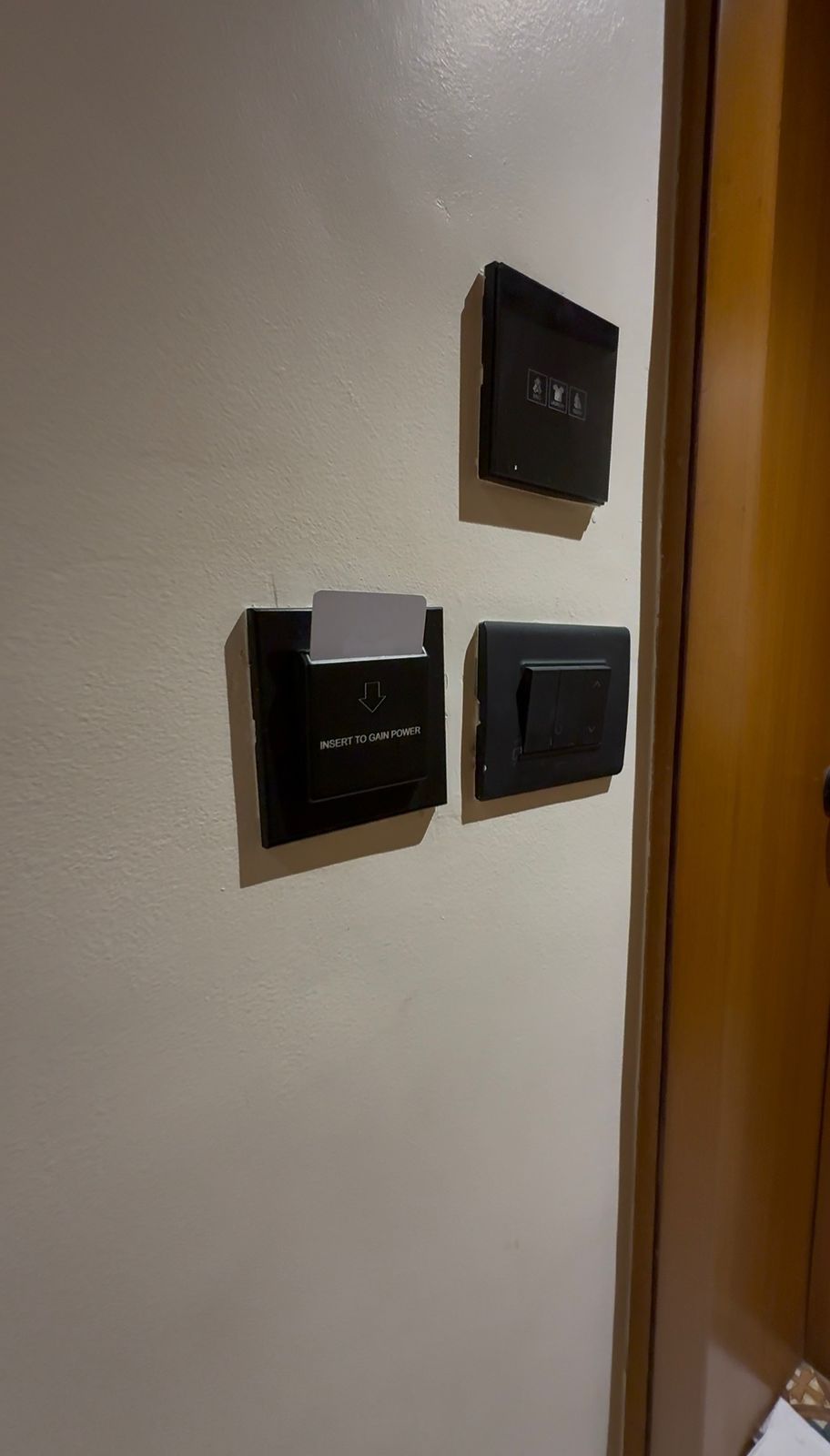 A door with three black intercom panels, one of which has a paper inserted into it.