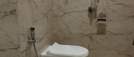 A bathroom with a toilet, a shower, and a marble floor.