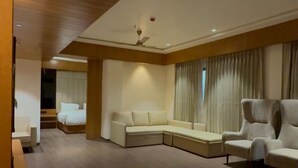 A spacious living area with a large L-shaped sectional sofa, a separate sofa, and a chair. The room has a wooden ceiling and a ceiling fan. - Hariganga S The Lake Attitude (Amravati)
