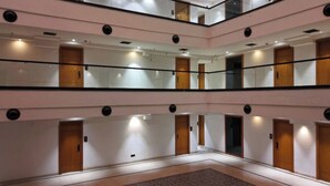 A multi-level hotel lobby with mirrored walls, wooden doors, and a central open space. - Hariganga S The Lake Attitude (Amravati)
