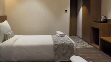 Ein Hotelzimmer mit zwei Betten, einem Deckenventilator und einer kleinen Sitzecke.