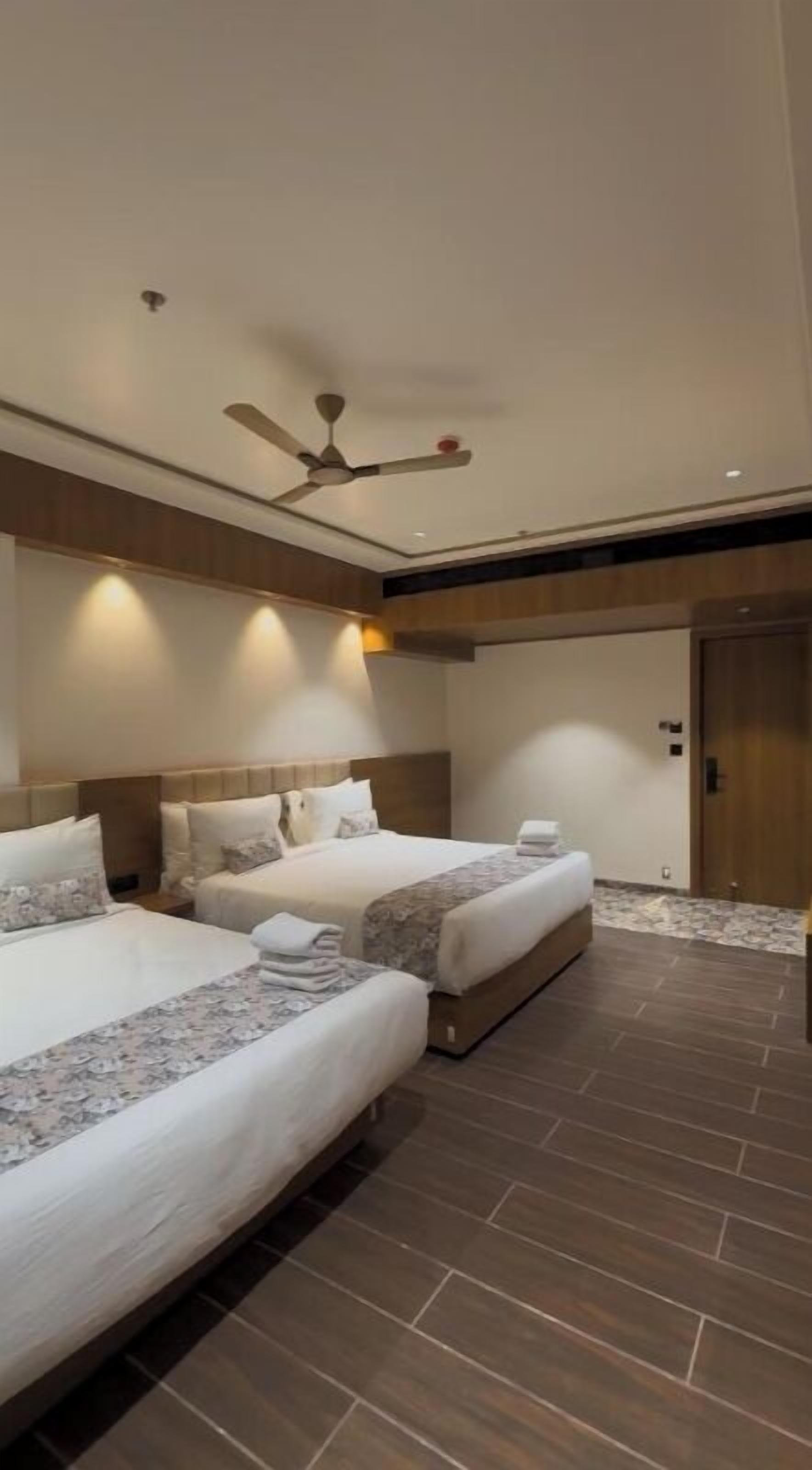 A hotel room with two beds, a ceiling fan, and a wooden door.