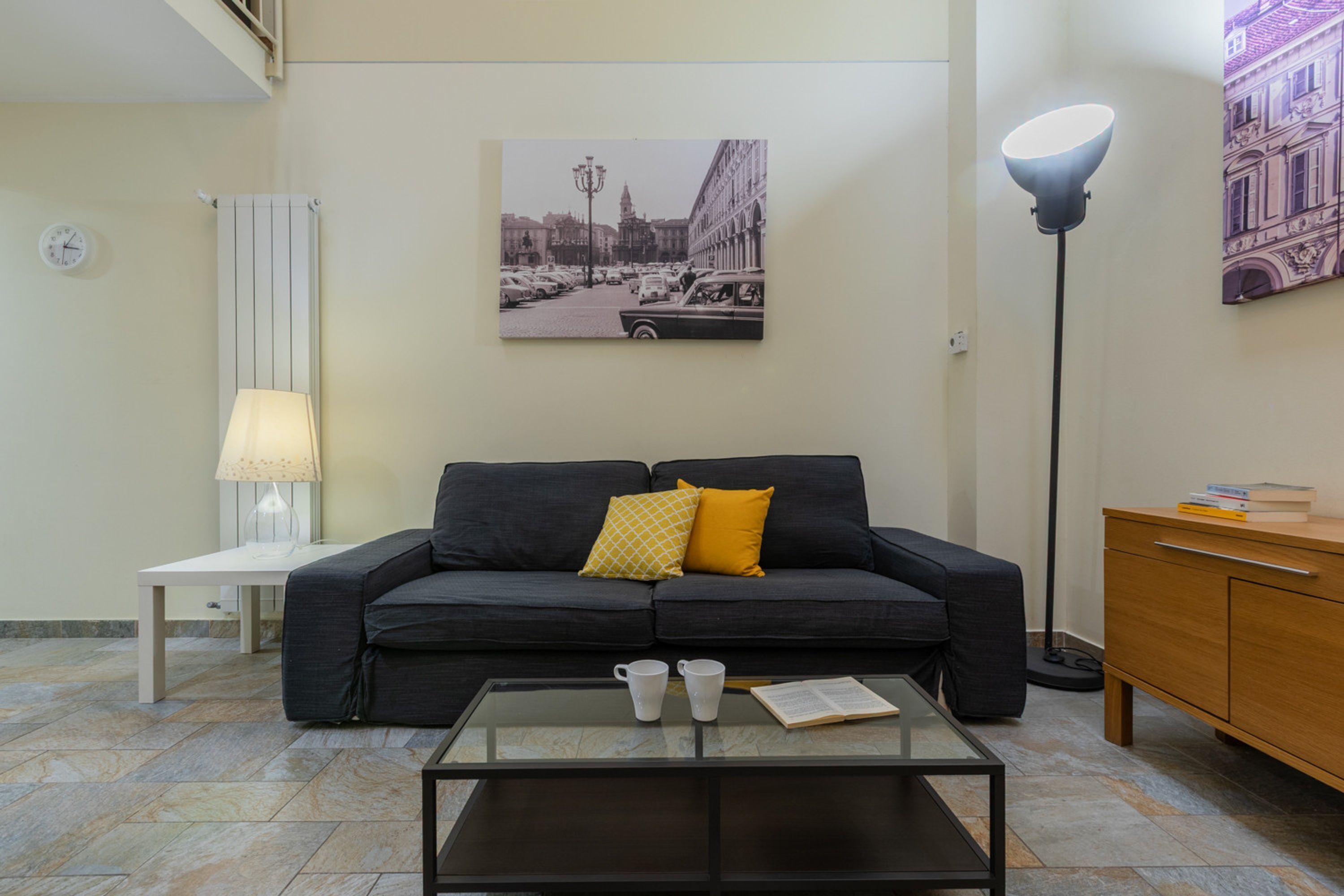 Ein modernes Wohnzimmer mit einer Couch, einem Couchtisch, einer Lampe und einem Gemälde an der Wand.