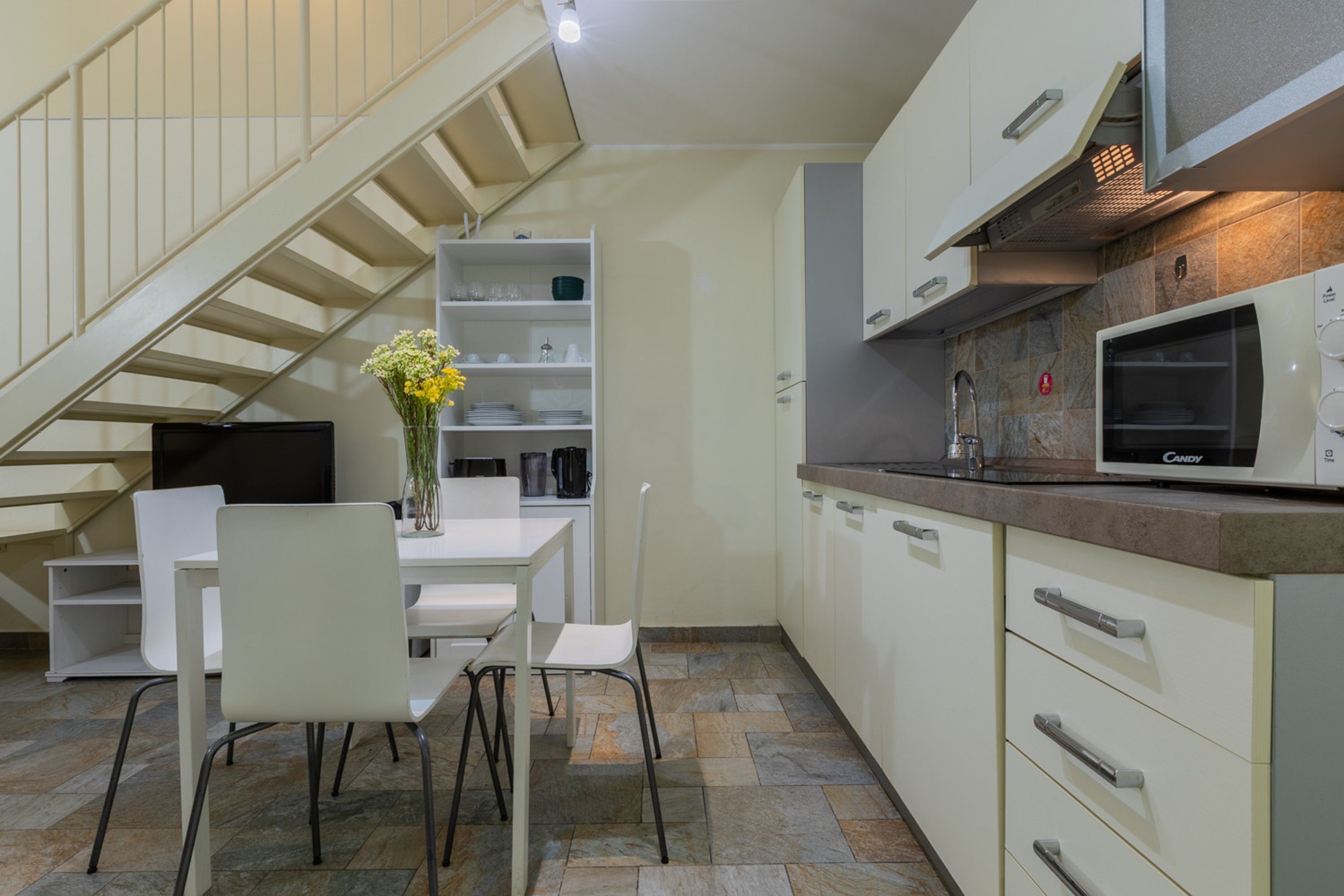 Una cocina moderna con armarios blancos, un microondas y un comedor con mesa y sillas.