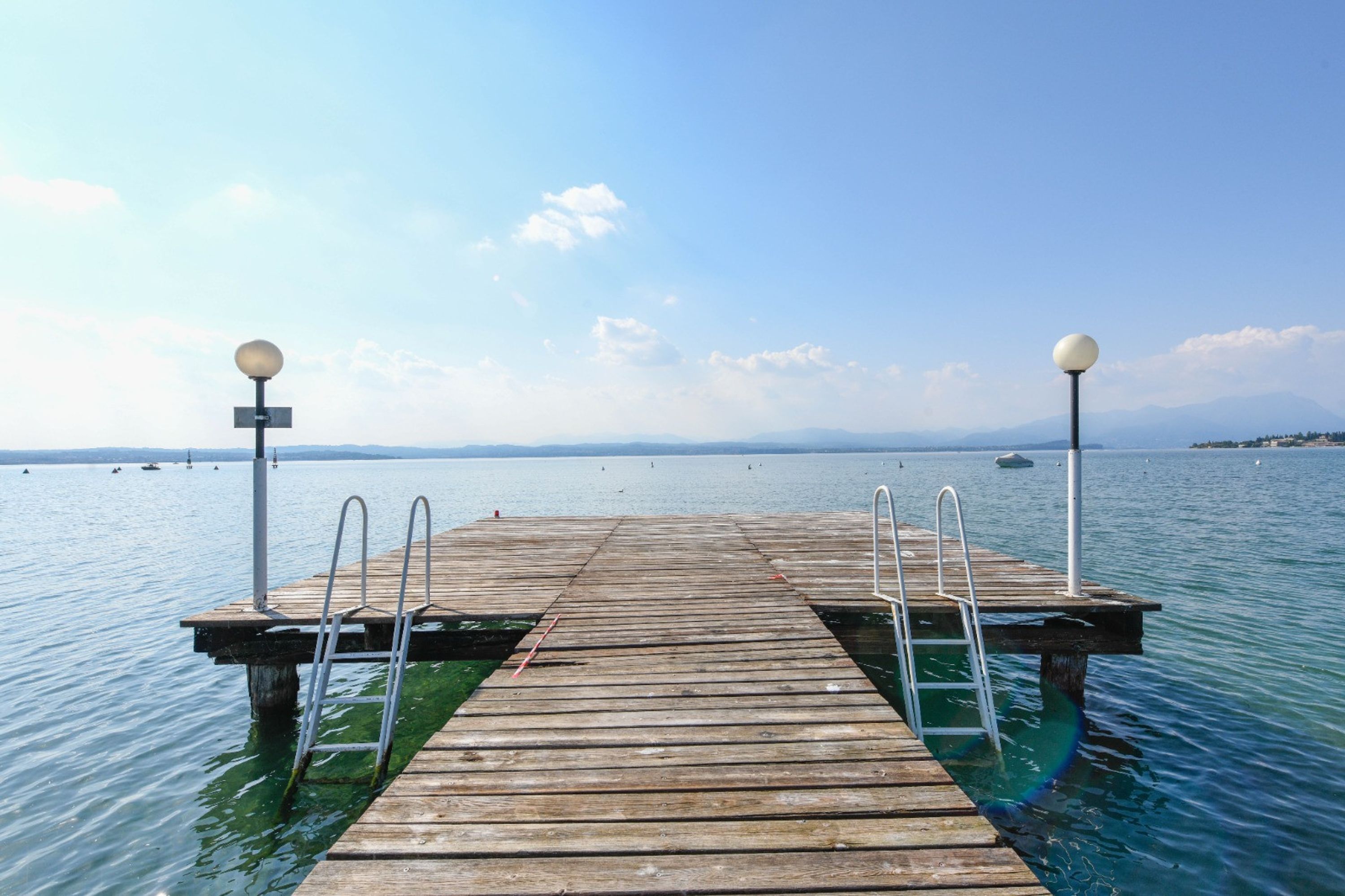 Un muelle de madera que se adentra en aguas tranquilas bajo cielos despejados.