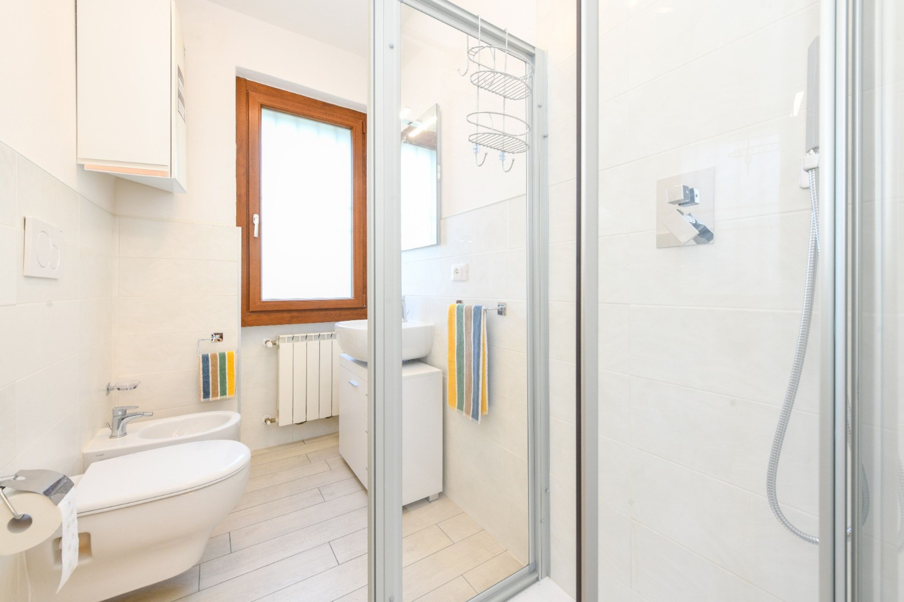 Uma casa de banho moderna com cabine de duche em vidro, lavatório branco e bidé.