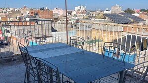 Terraza en la azotea con una mesa y sillas de metal, que ofrece vistas del paisaje urbano.