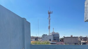 Una terraza en la azotea con un banco, suelo de piedra y vista despejada del horizonte urbano.