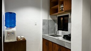 A compact kitchen with a water dispenser, a sink, and a stove.