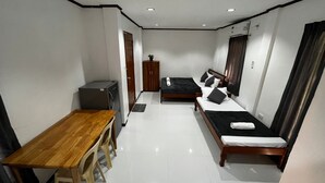 Une chambre d’hôtel compacte comprenant une table en bois, deux lits simples, une petite kitchenette et une armoire.