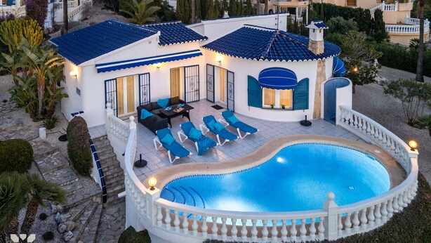 Una villa in stile mediterraneo con piscina, area salotto esterna e giardino curato.