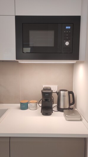 A kitchen with a microwave, coffee maker, kettle, and containers on the counter. - Brand New & Stylish Studio @ Salerno Center: The Perfect Base for Amalfi Coast (Salerno)