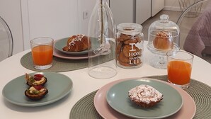Ein Esstisch mit Speisen, Orangensaftgläsern und einer Vase mit einer Blume.