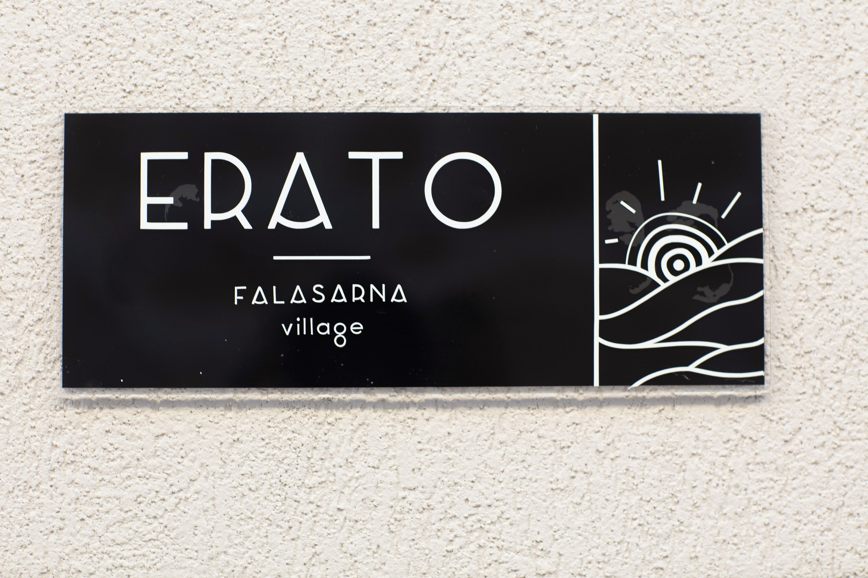 A black sign with white text reading "ERATO" and "FALASARNA village".