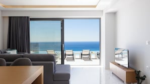 A modern living room with a sofa, a TV on a wooden stand, and a balcony with a view of the ocean. - Falasarna Village  (Kissamos)