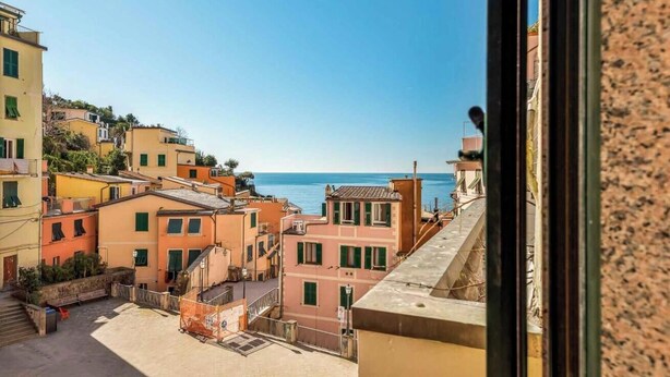 A coastal town with colorful buildings, a clear blue sea, and a view from a window overlooking the town. - Paradise 1, Marine Lands (Riomaggiore)
