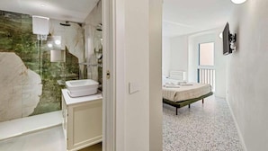 A modern bathroom with a marble wall, a white sink, and a glass shower enclosure. - Paradise 1, Marine Lands (Riomaggiore)