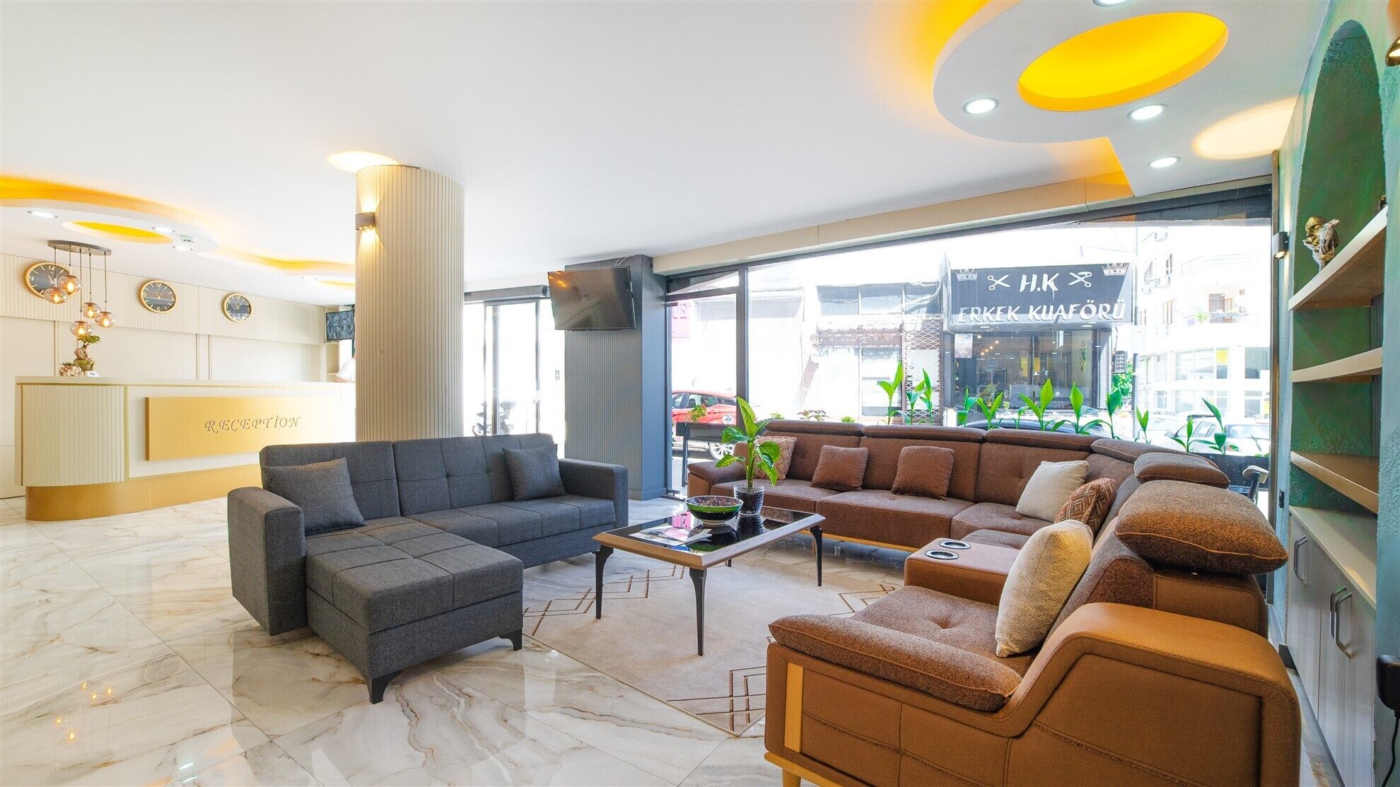 Un hall d’entrée moderne comprenant un comptoir de réception, des canapés, une table basse et une grande fenêtre donnant sur la rue.
