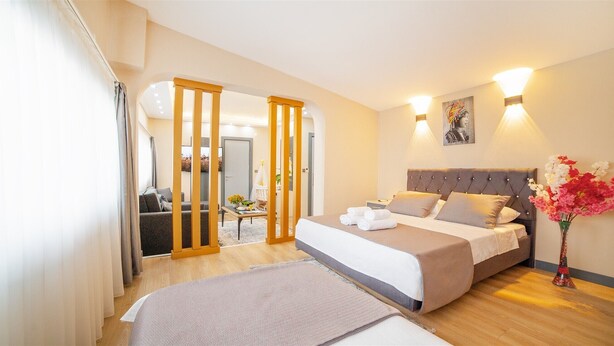 Une chambre d’hôtel avec un lit, un canapé, une cloison en bois et une vue sur l’extérieur.