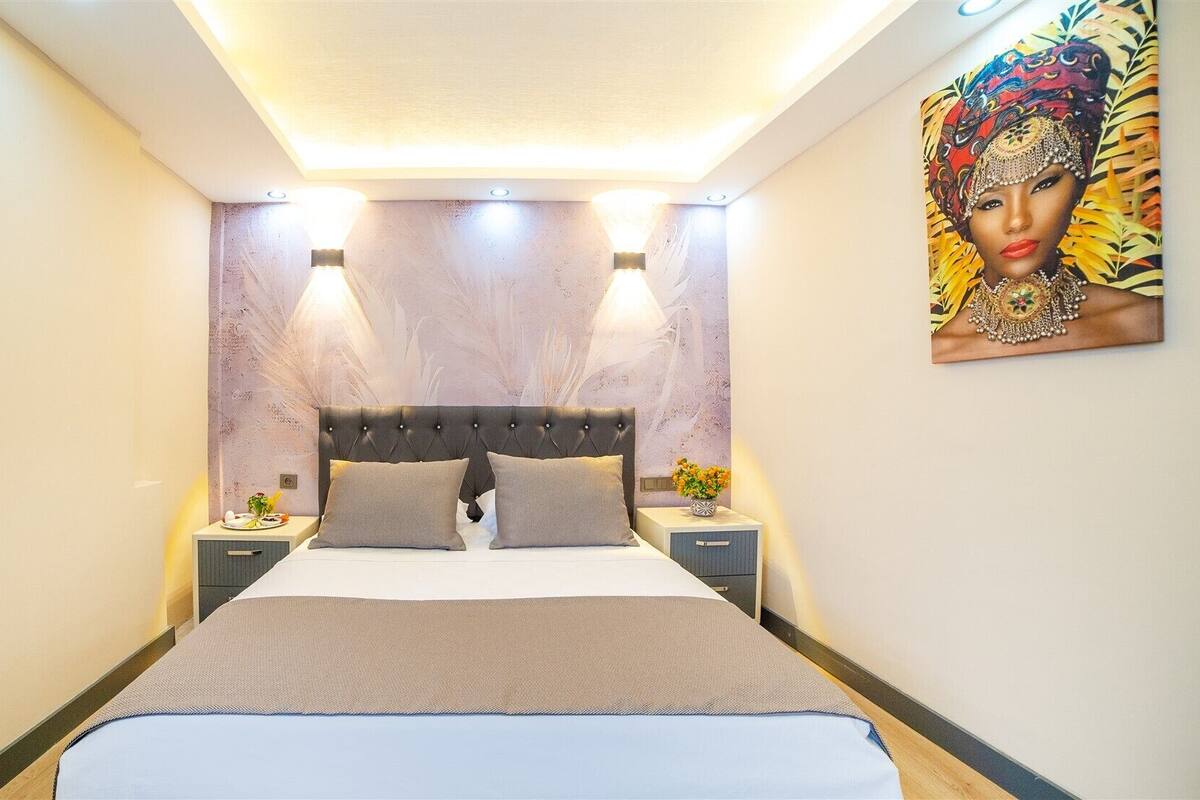 Un dormitorio moderno con una cama grande, dos mesitas de noche y una obra de arte colgada en la pared.