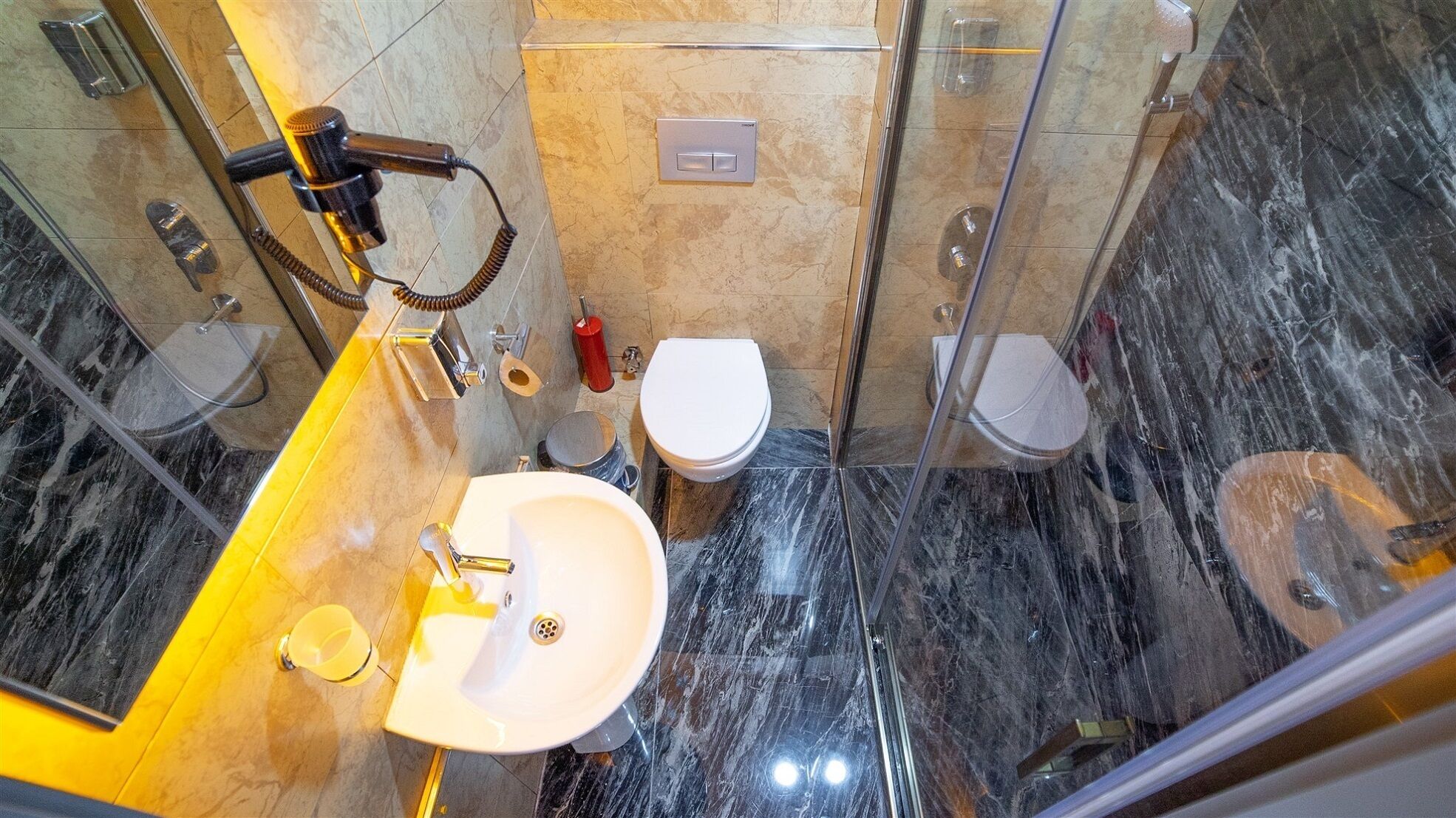 A bathroom with a marble floor, a white sink, two toilets, and a shower area.