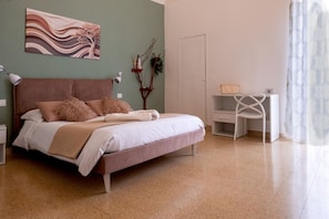 Un dormitorio con cama, mesitas de noche, un escritorio y una silla.