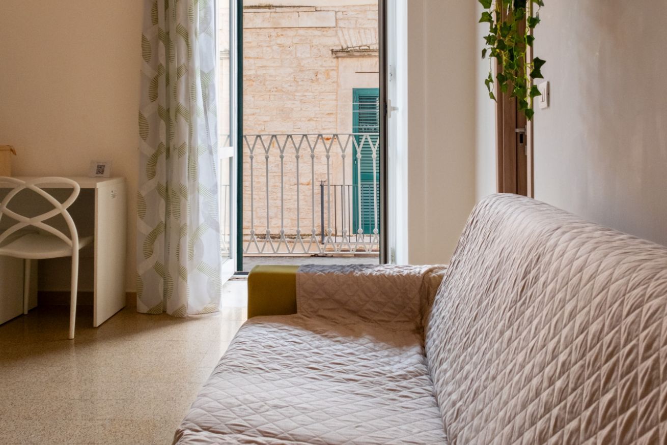 Une chambre à coucher avec un lit, un bureau et une vue sur un immeuble par la fenêtre.