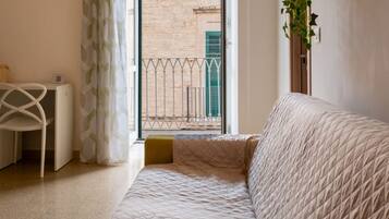 Une chambre à coucher avec un lit, un bureau et une vue sur un immeuble par la fenêtre.