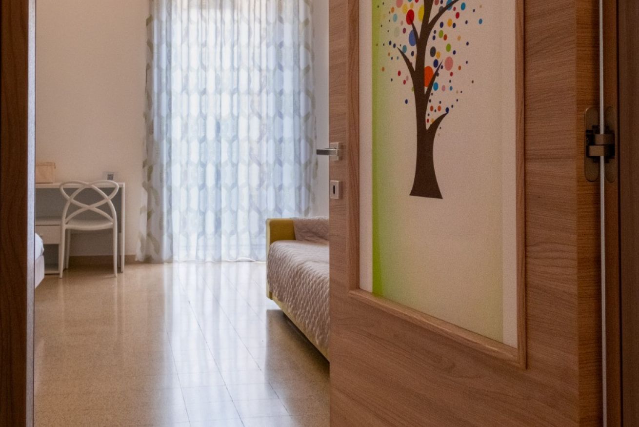 Une chambre avec un lit, un bureau et une fenêtre avec des rideaux.