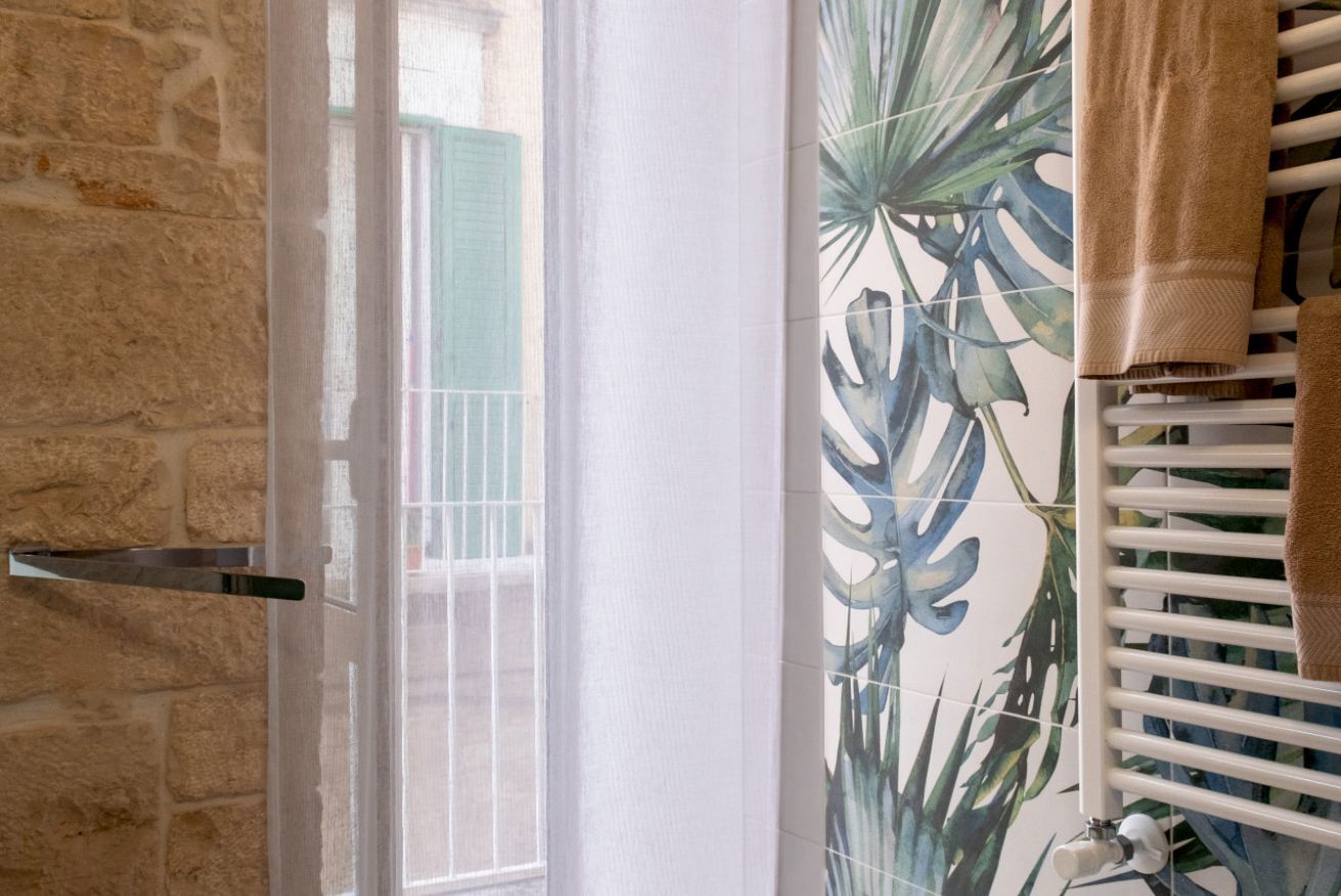 Ein Badezimmer mit Steinwand, Fenster mit Metallgriff und Handtuchhalter mit Handtuch.