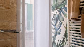 Ein Badezimmer mit Steinwand, Fenster mit Metallgriff und Handtuchhalter mit Handtuch.
