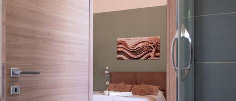 Un dormitorio con cama, una obra de arte en la pared, una puerta y una zona de ducha.